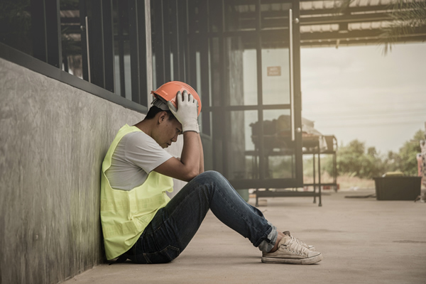 Worried contractor sitting in front of a cement wall