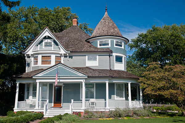 A Victorian house with a wraparound porch and an intricate turreted roof
