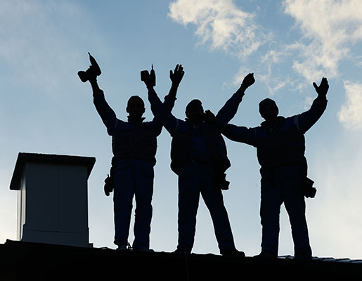 A silhouette of a roofing crew on a roof.