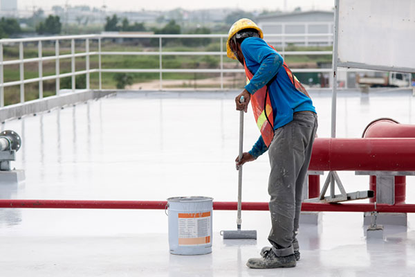 A roofer applies a commercial roof coating.