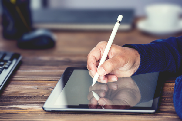 Individual using a pen stylus to sign a contract on a tablet