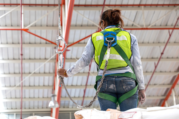 woman in PFAS harness clipping onto a lanyard while on a jobsite