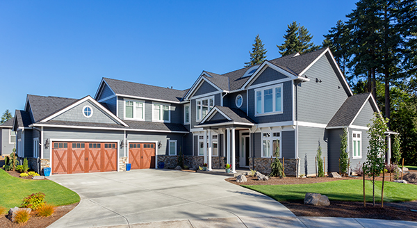 A gray house with a new asphalt roof against a blue sky.