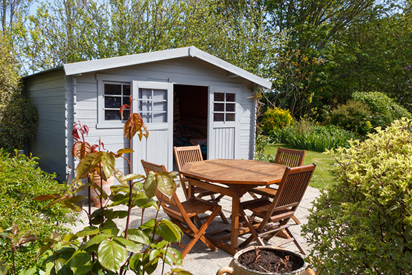 Neat garden with shed and wooden table and chairs.