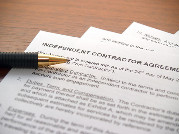 independent contractor agreement paperwork on desk with pen