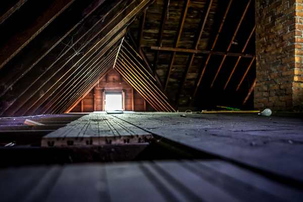 An unfinished attic with the sun shining through the vent