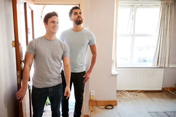 Couple, two men, opening the door on their new fixer-upper home