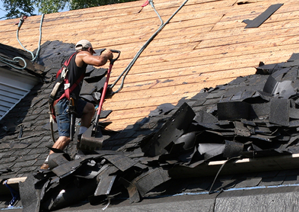 Roofing worker removing shingles