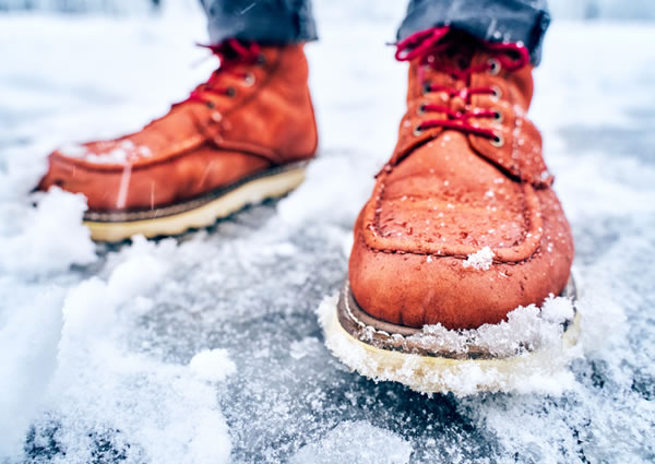 Close-up image of a person's boots in snowy, icy conditions