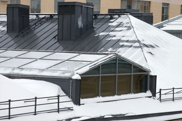 Steeply sloped standing seam roof atop a building covered in snow.