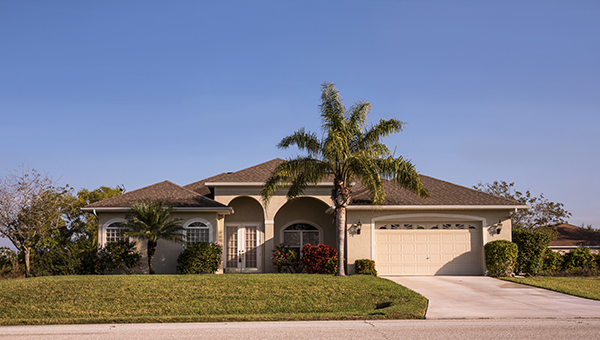 Southwest Florida concrete block and stucco home in the countryside with palm trees and grass lawn.