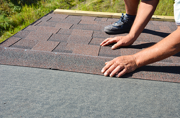 Contractor installing asphalt roof shingles in St. Louis.