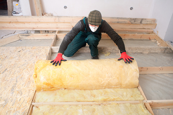 Worker laying insulation in an attic floor