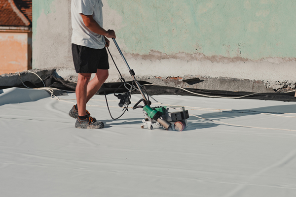 Roofer using a welding tool on wheels on a membrane roof